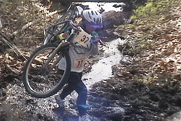 Andrina carries her bike through the stream.